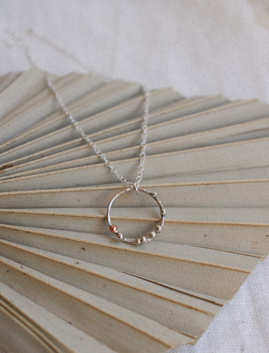 sterling silver open circle necklace with tiny silver and copper ball detail